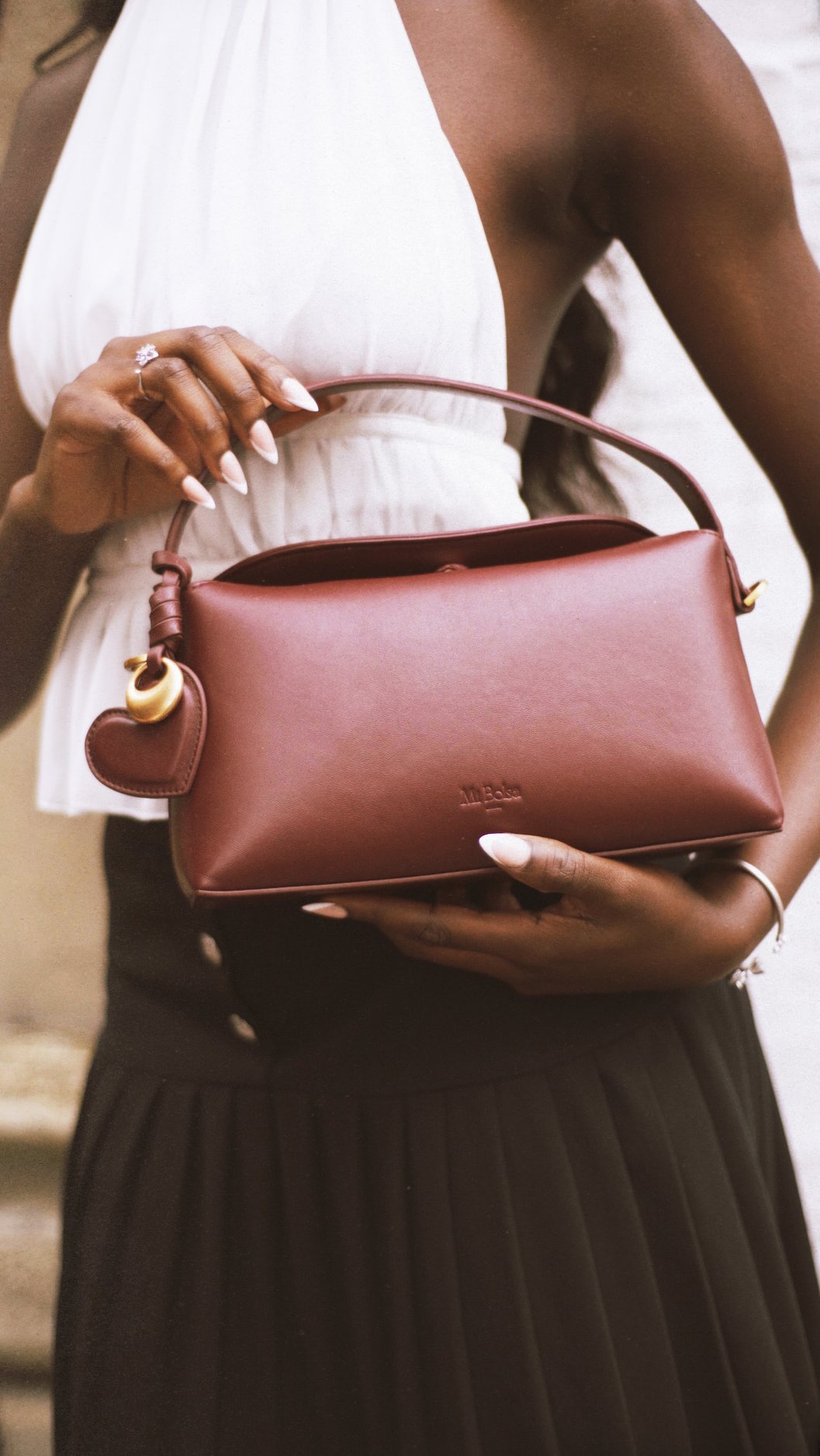Woman holding Mi Bolsa Camilla bag in black and white chic outfit.